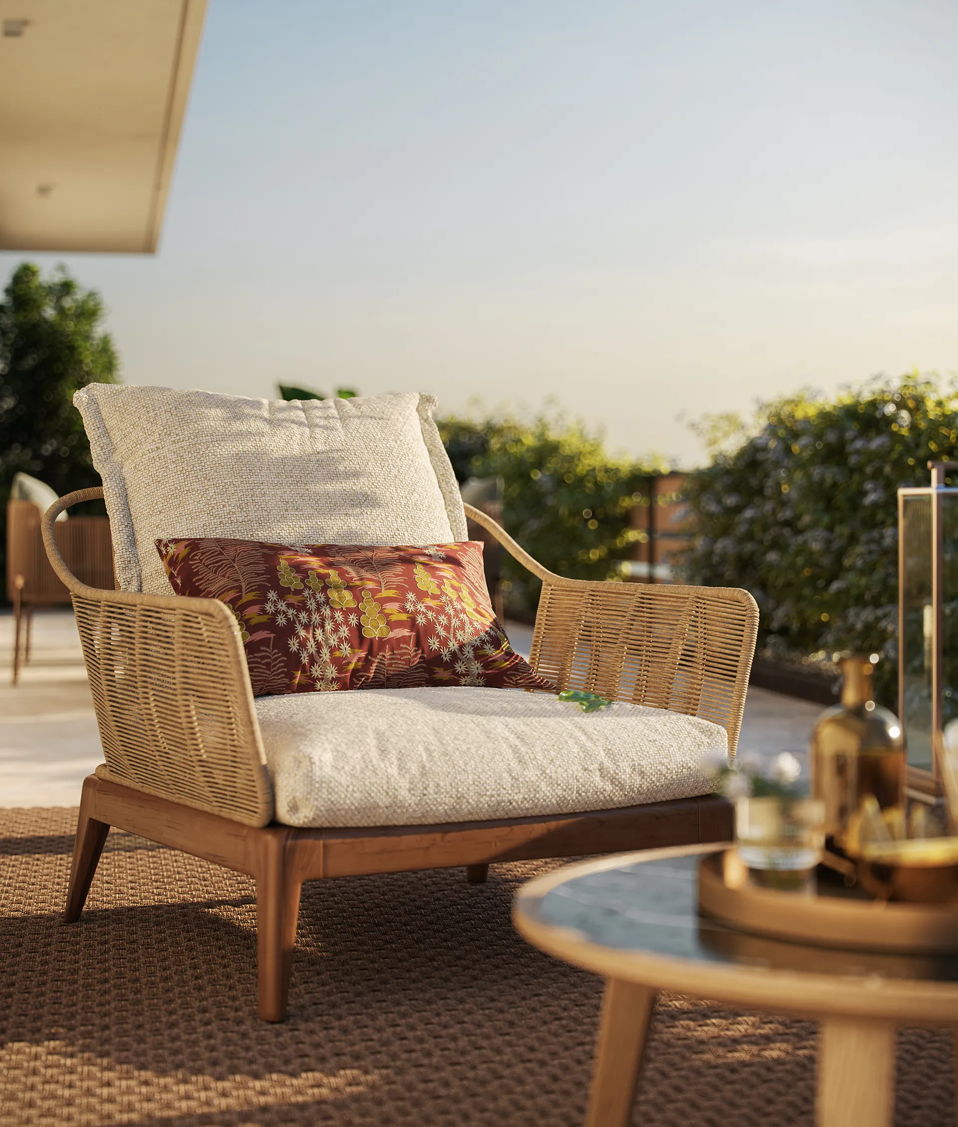 Poltrona da esterno in legno con struttura intrecciata, cuscino beige e cuscino decorativo rosso con motivi floreali, su un tappeto marrone in un ambiente soleggiato.